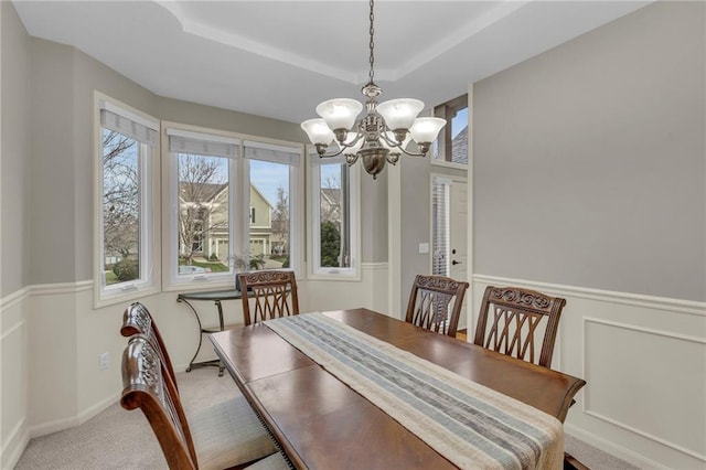 dining room featuring an inviting chandelier, a tray ceiling, and carpet floors