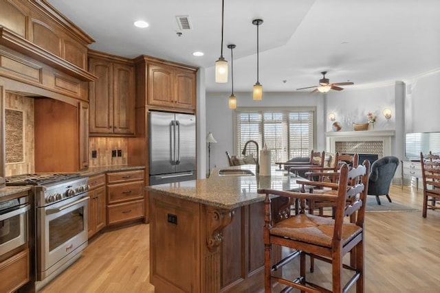 kitchen featuring pendant lighting, light stone counters, sink, and appliances with stainless steel finishes