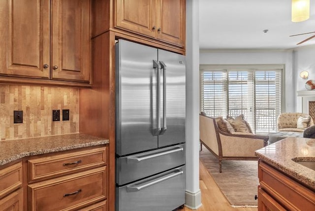 kitchen with high end refrigerator, light wood-type flooring, light stone counters, and ceiling fan