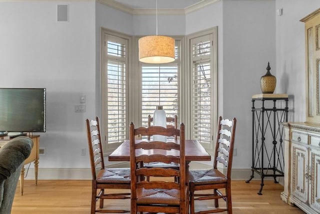 dining room with light wood-type flooring and ornamental molding