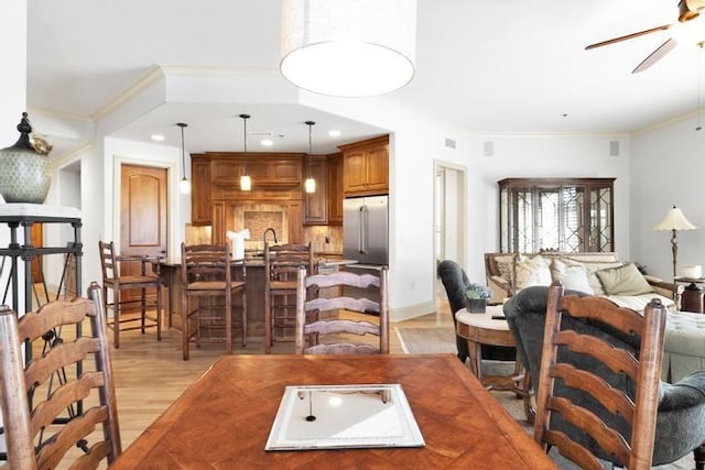 living room featuring light hardwood / wood-style flooring, ceiling fan, ornamental molding, and sink