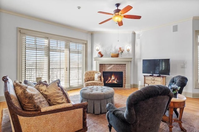 living room featuring hardwood / wood-style flooring, ceiling fan, ornamental molding, and a brick fireplace