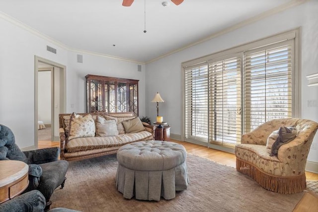 living room featuring crown molding, light hardwood / wood-style flooring, and ceiling fan