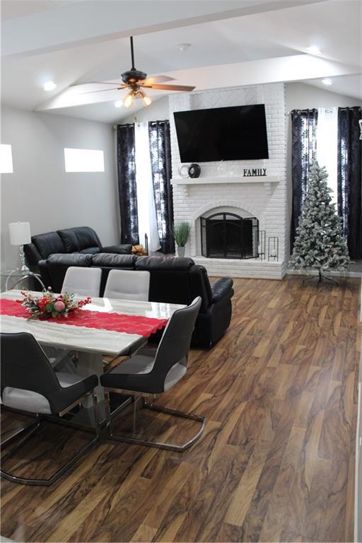 dining area with hardwood / wood-style flooring, ceiling fan, and a brick fireplace