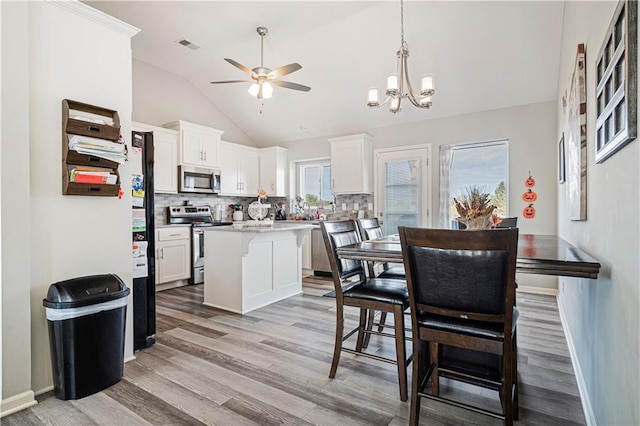 kitchen with backsplash, white cabinets, a kitchen breakfast bar, a kitchen island, and stainless steel appliances