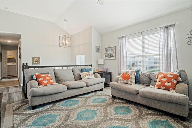 living room featuring washer / clothes dryer, vaulted ceiling, and hardwood / wood-style flooring