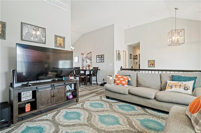 living room with hardwood / wood-style floors, lofted ceiling, and an inviting chandelier