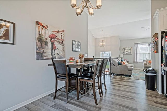 dining area featuring wood-type flooring, vaulted ceiling, and an inviting chandelier