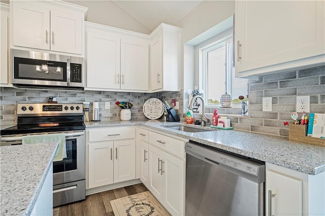 kitchen with backsplash, white cabinets, sink, appliances with stainless steel finishes, and light stone counters