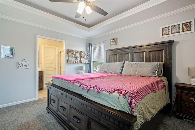 carpeted bedroom with a raised ceiling, connected bathroom, ceiling fan, and ornamental molding