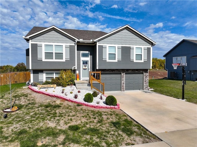 raised ranch featuring a garage and a front lawn