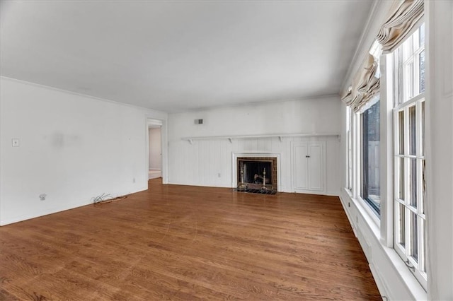 unfurnished living room with a fireplace with flush hearth, visible vents, and wood finished floors