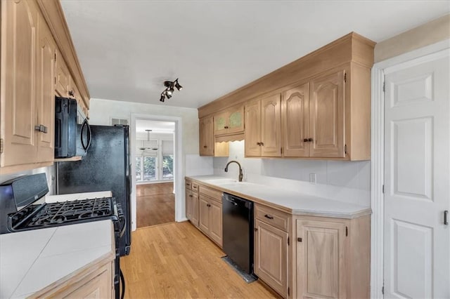 kitchen with light brown cabinets, black dishwasher, light wood-style floors, gas stove, and a sink