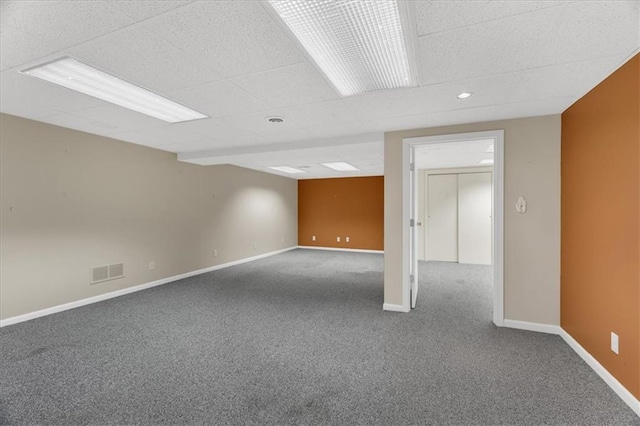 unfurnished room with visible vents, a drop ceiling, baseboards, and carpet floors