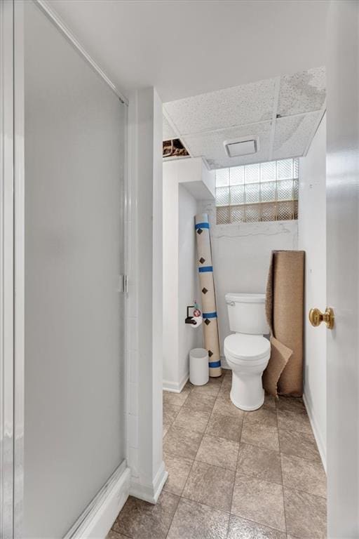 full bath featuring a drop ceiling, a stall shower, and toilet