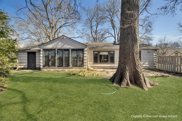 rear view of property with a yard and fence