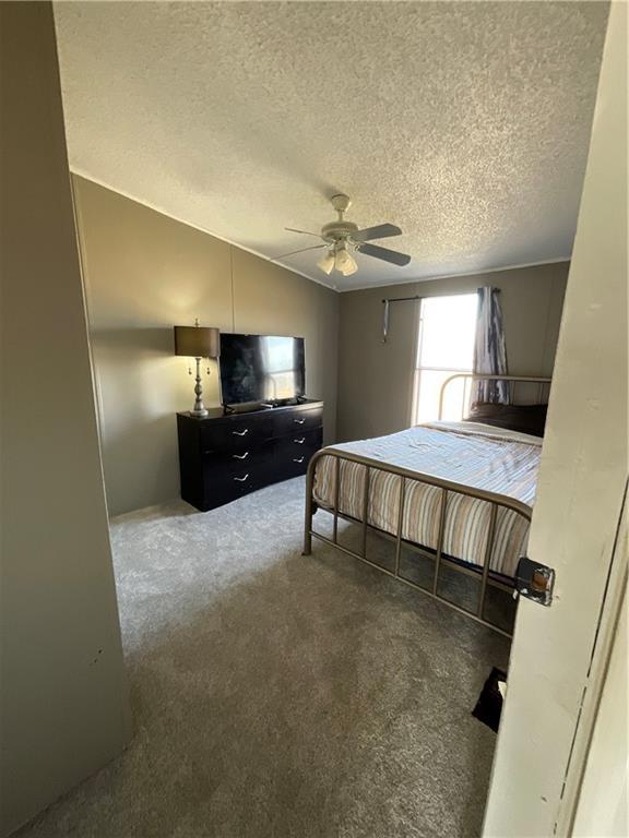 bedroom featuring vaulted ceiling, ceiling fan, a textured ceiling, and carpet