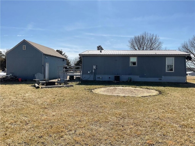 rear view of property with metal roof and a lawn