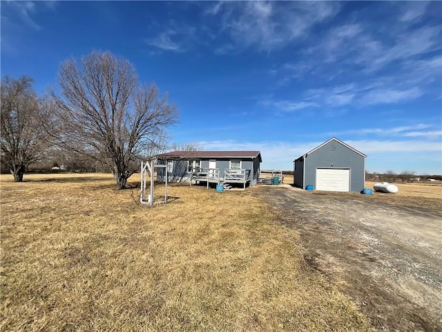 view of front of property with an outdoor structure, a detached garage, and dirt driveway