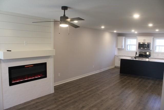 kitchen featuring stainless steel appliances, ceiling fan, dark wood-type flooring, sink, and white cabinets