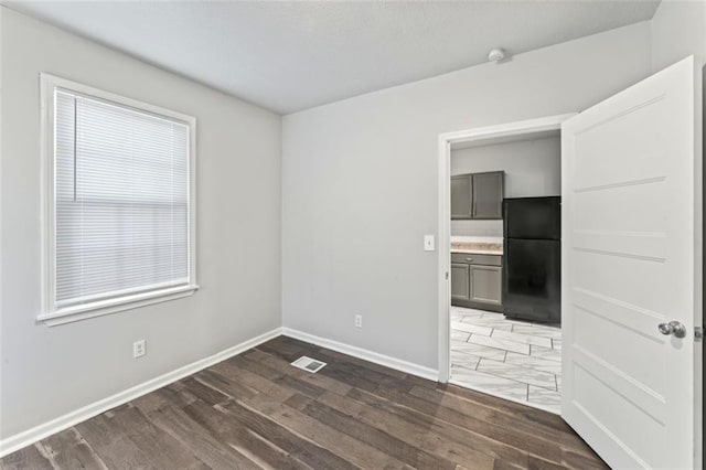 spare room featuring dark wood-type flooring and a wealth of natural light