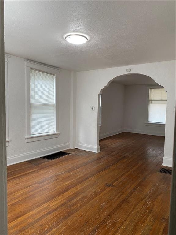 unfurnished room with a textured ceiling and dark wood-type flooring