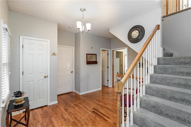 entryway with hardwood / wood-style floors, a textured ceiling, and a chandelier