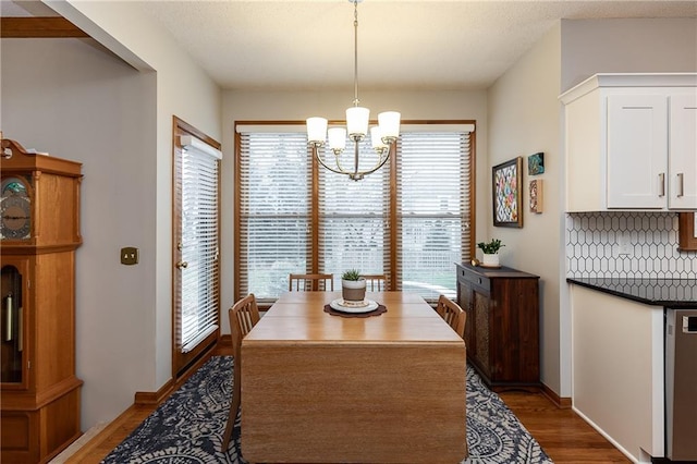 dining area with dark wood-type flooring and a notable chandelier