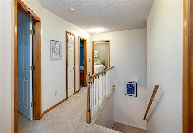 corridor featuring light colored carpet and a textured ceiling