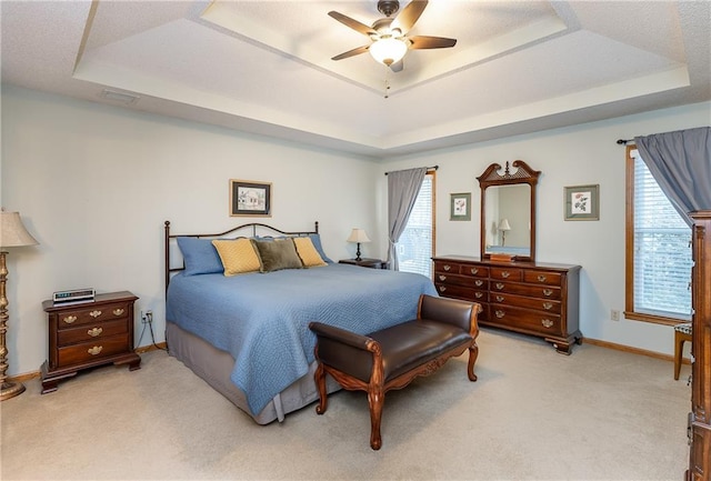 carpeted bedroom featuring ceiling fan and a raised ceiling