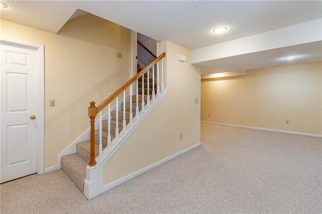 stairway featuring a textured ceiling and carpet