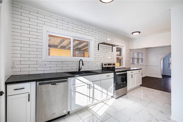 kitchen with appliances with stainless steel finishes, white cabinets, decorative backsplash, and sink