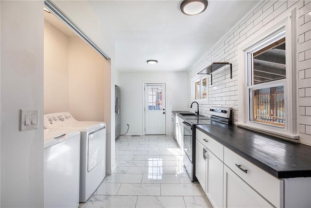 kitchen featuring stainless steel appliances, sink, white cabinetry, tasteful backsplash, and washer and clothes dryer