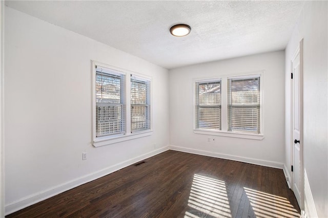 unfurnished room with a textured ceiling and dark hardwood / wood-style floors