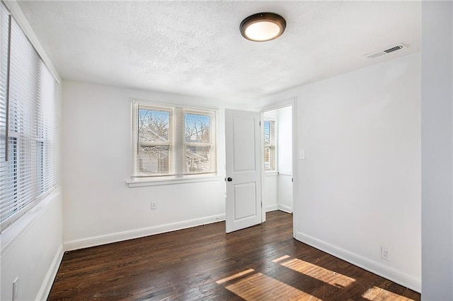 unfurnished room with a textured ceiling and dark hardwood / wood-style floors