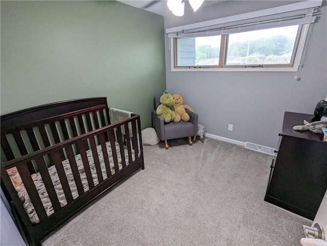 carpeted bedroom with ceiling fan and a nursery area