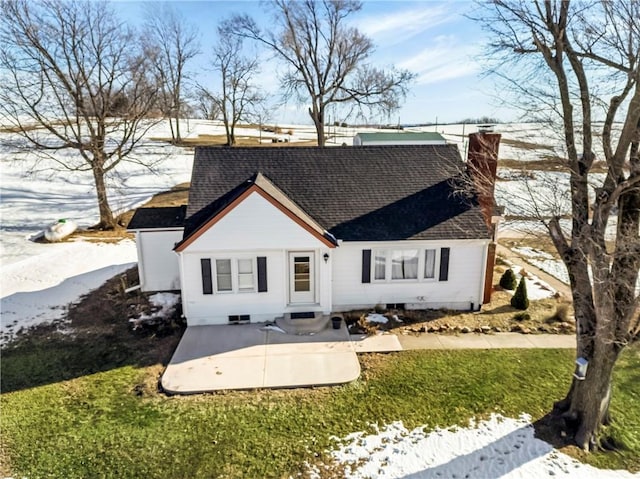 snow covered house with a patio and a lawn