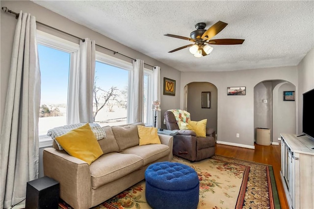 living room with ceiling fan, dark hardwood / wood-style flooring, and a textured ceiling