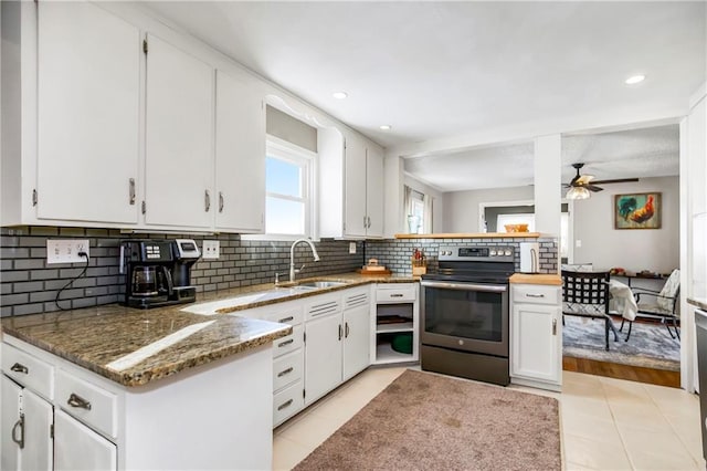 kitchen with sink, white cabinets, light tile patterned floors, electric range, and decorative backsplash