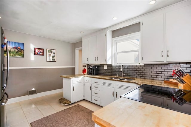 kitchen with tasteful backsplash, white cabinetry, sink, light stone counters, and light tile patterned flooring