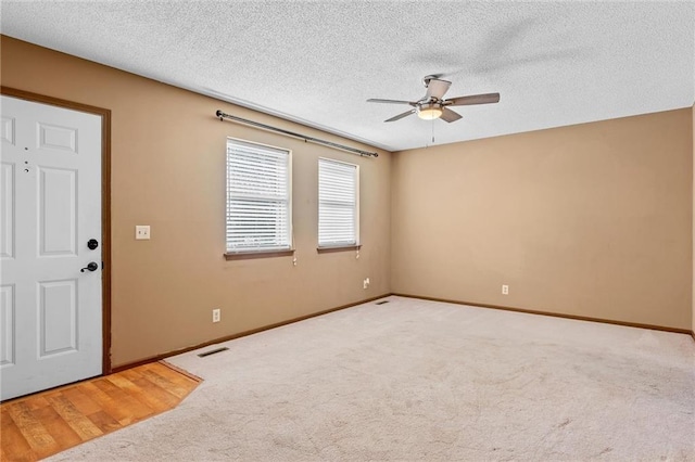 spare room with a textured ceiling, ceiling fan, and carpet flooring