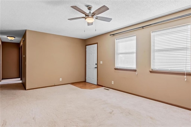 carpeted spare room featuring a textured ceiling and ceiling fan