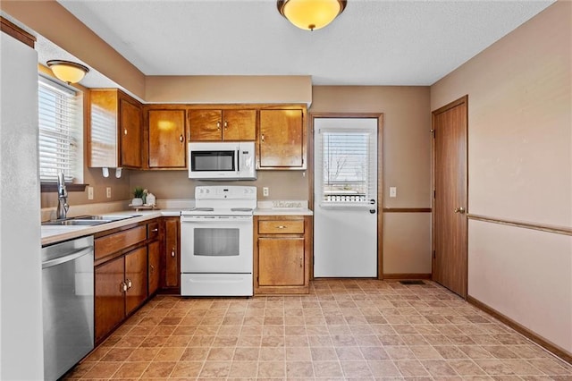 kitchen with sink, white appliances, and a healthy amount of sunlight