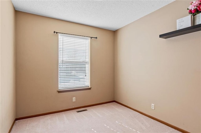 carpeted empty room featuring a textured ceiling