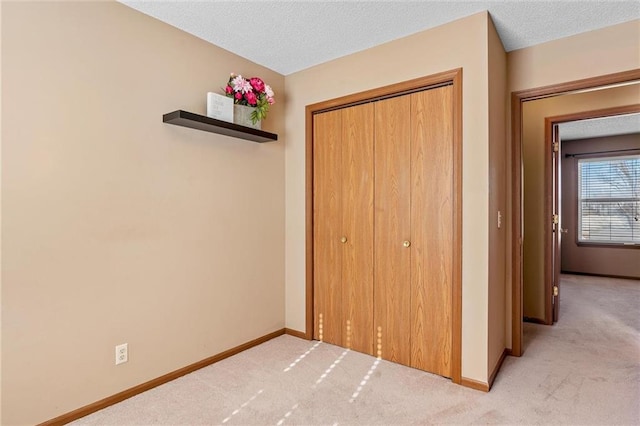 unfurnished bedroom featuring light colored carpet, a closet, and a textured ceiling