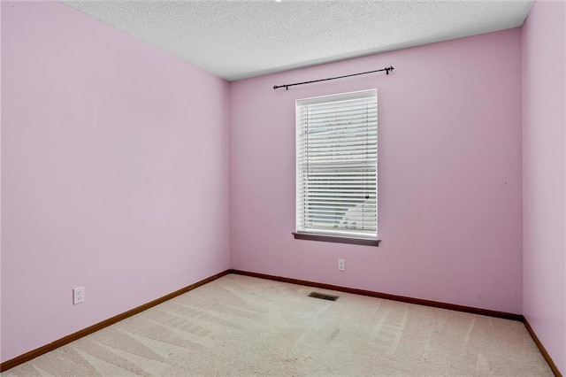 unfurnished room featuring a textured ceiling and light carpet