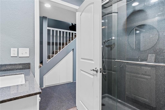 bathroom featuring a shower with door and vanity