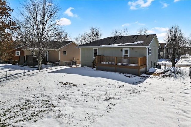 snow covered back of property with a deck