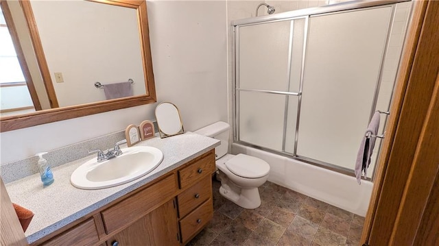 full bathroom featuring toilet, bath / shower combo with glass door, and vanity