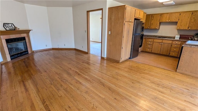 1205 Wentley Dr, Hiawatha, KS 66434 - kitchen featuring freestanding refrigerator, dark countertops, light wood-type flooring, and brown cabinets